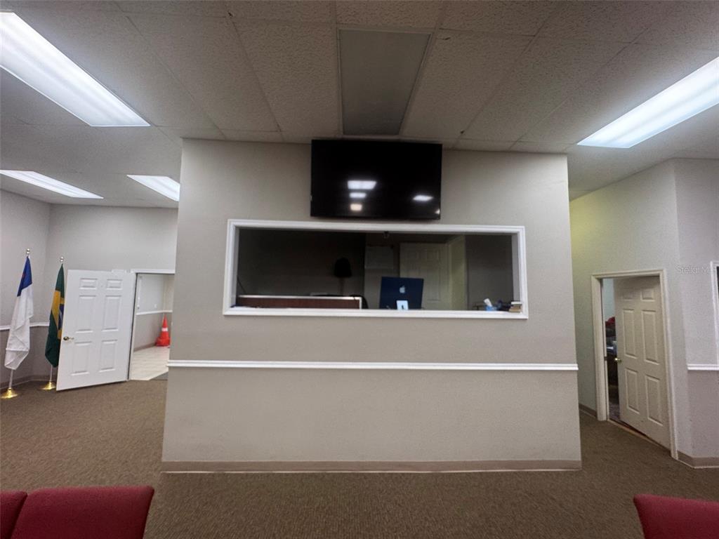 A room with a central wall featuring a pass-through window and a mounted television — 11601 S ORANGE BLOSSOM TRAIL UNIT 203, ORLANDO, FL