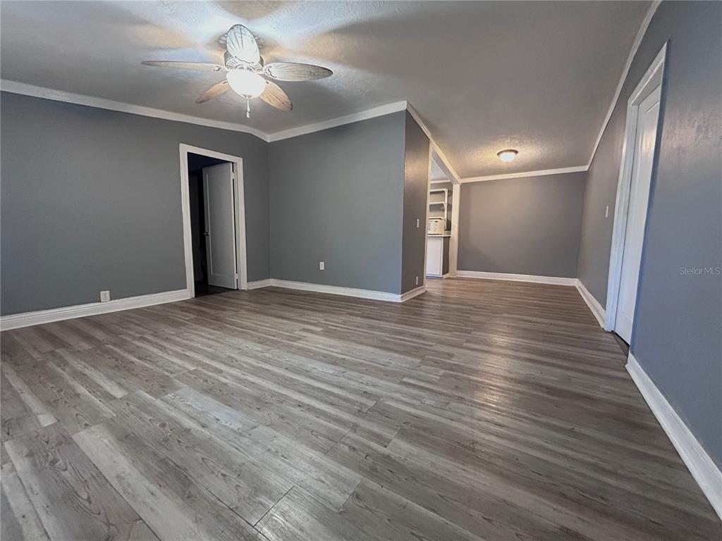 An empty room with gray walls, white trim, and wood-look flooring features a ceiling fan — 10638 BAY HILLS CIRCLE, THONOTOSASSA, FL