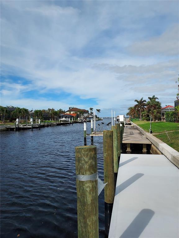 A view of a canal with wooden pilings, a concrete dock, and waterfront homes — 2200 PALM TREE DRIVE, PUNTA GORDA, FL