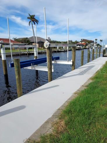 A boat lift with blue bunks is installed along a concrete seawall on a canal — 2200 PALM TREE DRIVE, PUNTA GORDA, FL