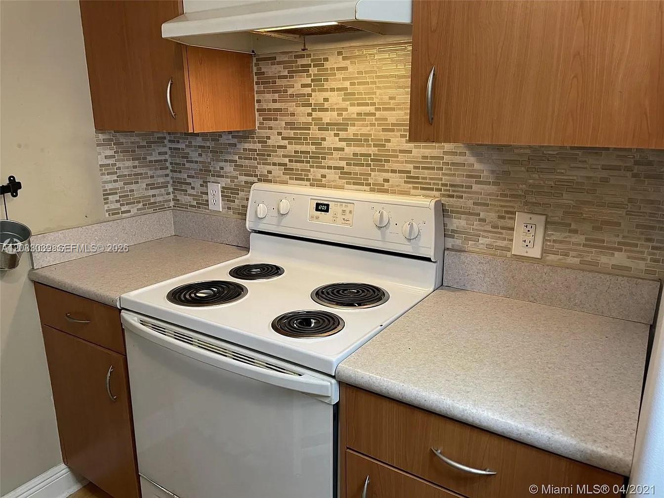 A kitchen features wood cabinets, a white electric stove, and a tiled backsplash — 816 NW 11th St # 704, Miami FL 33136, MIAMI, FL