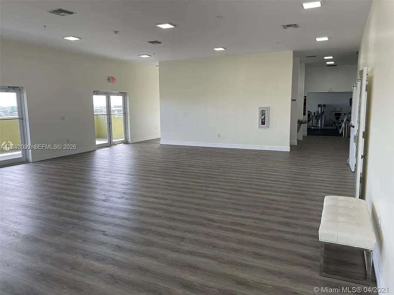 A spacious room features light wood-look flooring, recessed lighting, and a doorway to a gym — 816 NW 11th St # 704, Miami FL 33136, MIAMI, FL
