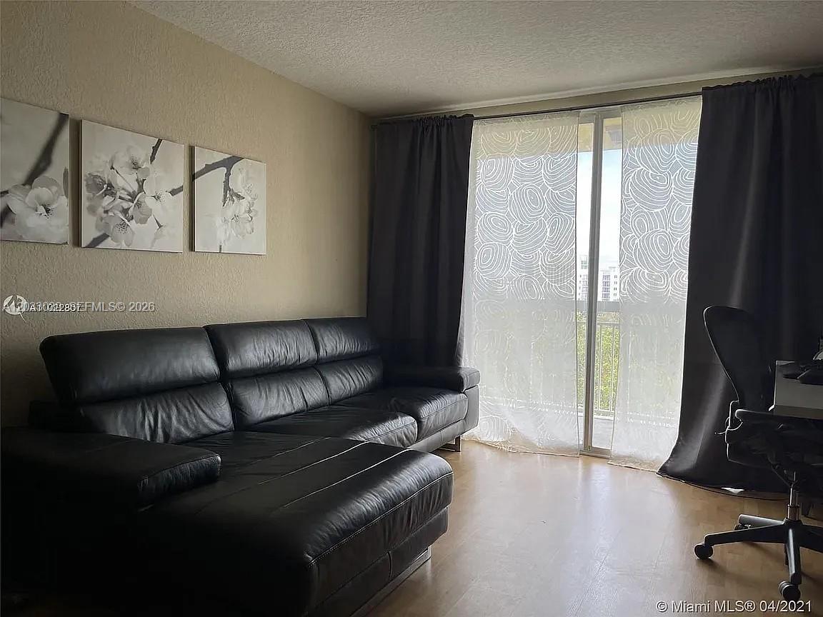 A living room features a black leather sectional sofa, wall art, and a sliding glass door — 816 NW 11th St # 704, Miami FL 33136, MIAMI, FL