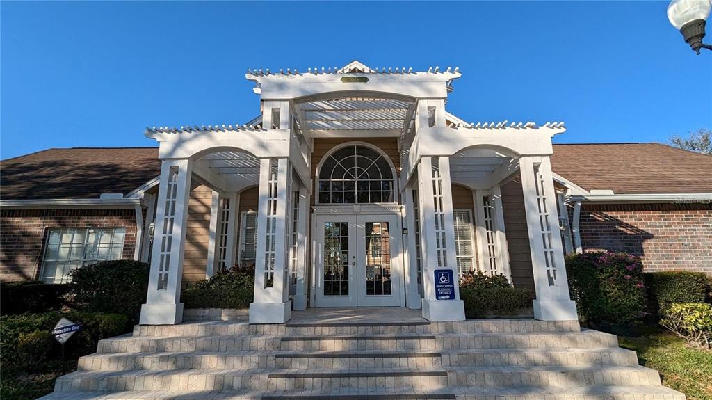 The exterior of a building features a white pergola entrance with steps leading to double doors — 4400 THORNBRIAR LANE UNIT A202, ORLANDO, FL