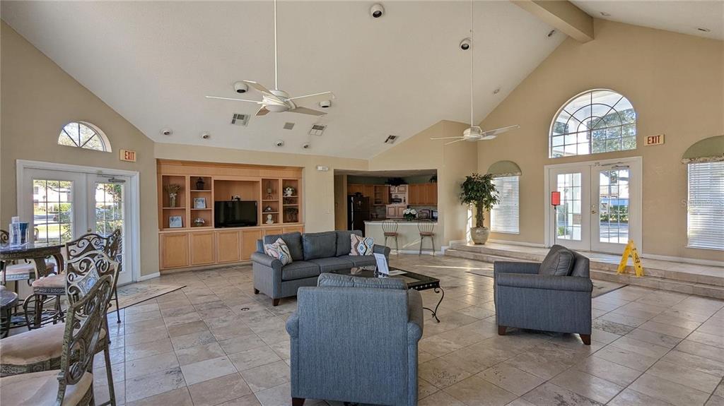 A spacious community clubhouse features tile flooring, vaulted ceilings, a kitchen, and lounge seating — 4400 THORNBRIAR LANE UNIT A202, ORLANDO, FL