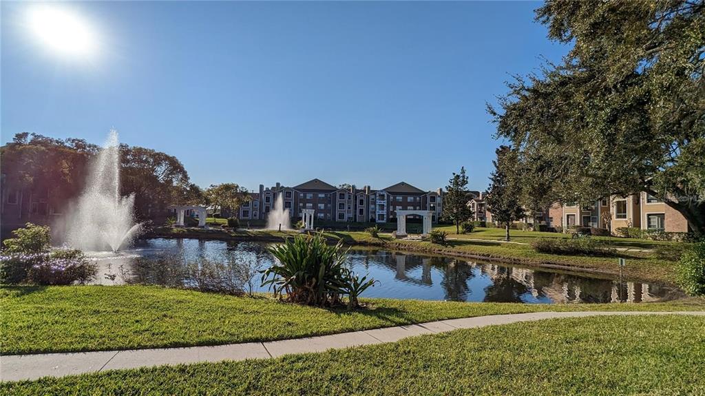 A pond with two fountains sits in front of a multi-story apartment complex — 4400 THORNBRIAR LANE UNIT A202, ORLANDO, FL