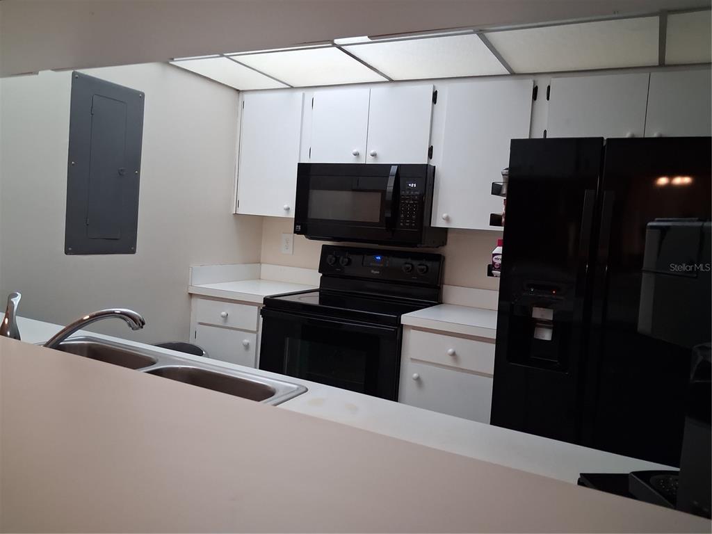 A kitchen features white cabinets, black appliances, a double sink, and a drop ceiling — 3341 CAMELOT DRIVE UNIT 3341, HAINES CITY, FL