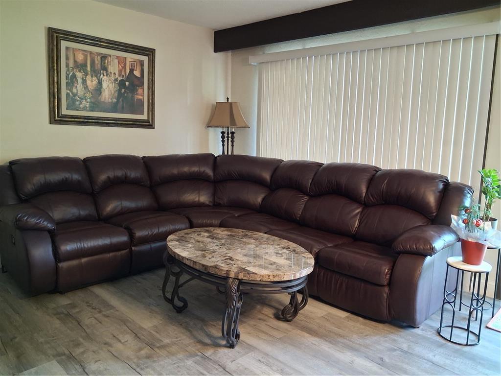 A living room features a large brown leather sectional, a marble-topped coffee table, and blinds — 3341 CAMELOT DRIVE UNIT 3341, HAINES CITY, FL