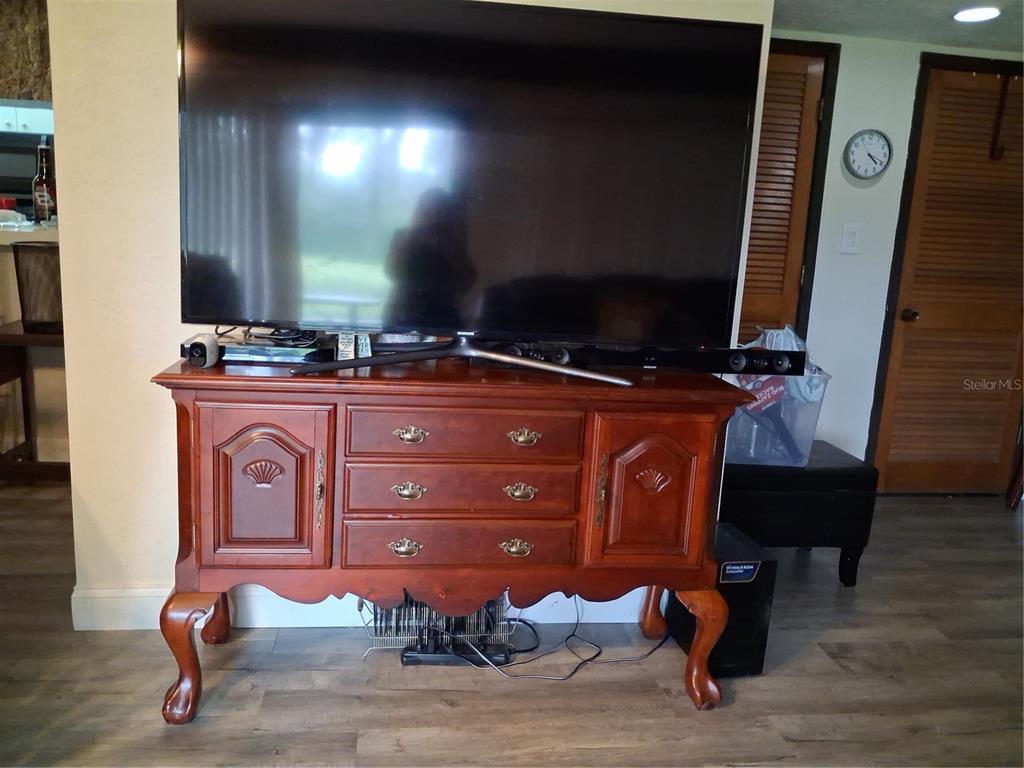A large television sits on a wooden cabinet with drawers in a living room — 3341 CAMELOT DRIVE UNIT 3341, HAINES CITY, FL