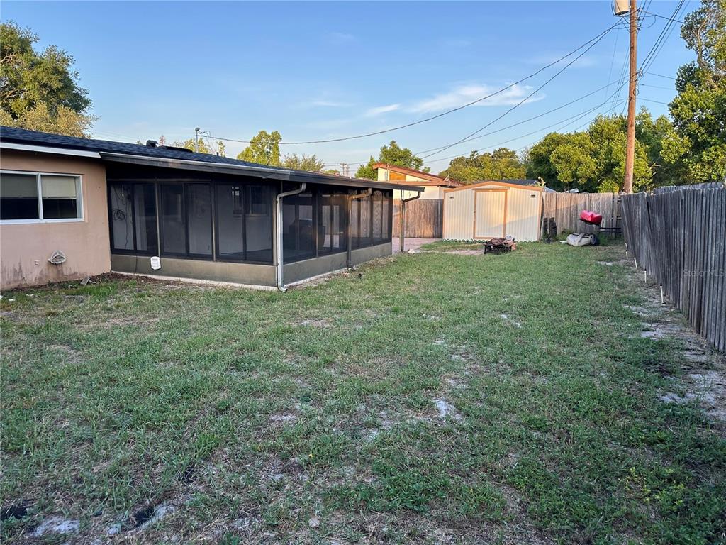 A backyard features a screened-in porch, a detached storage shed, and a wooden fence — 522 WILSHIRE DRIVE, CASSELBERRY, FL