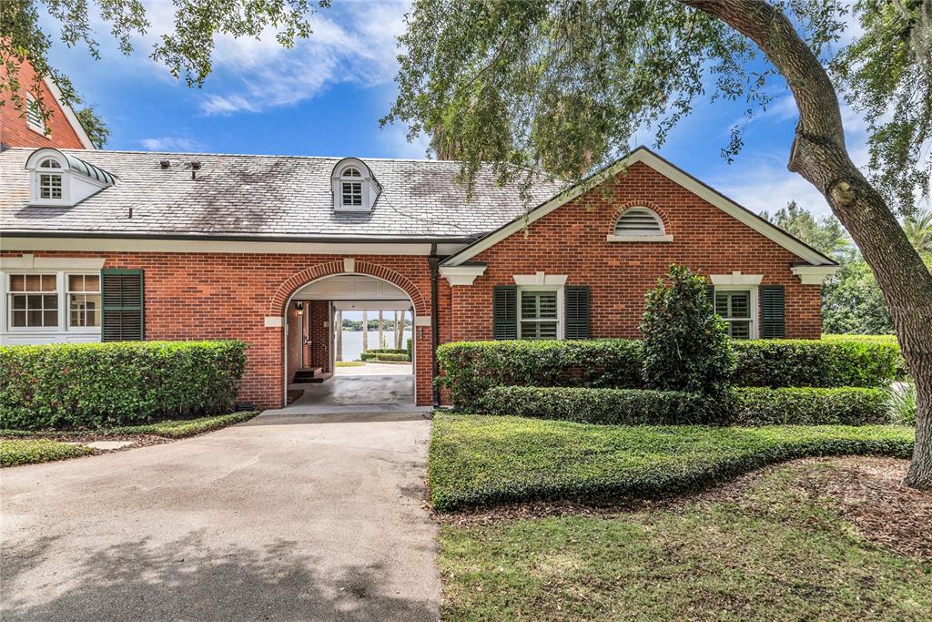 A brick house exterior features a central arched breezeway leading to a view of water — 1530 WATERWITCH DRIVE, ORLANDO, FL