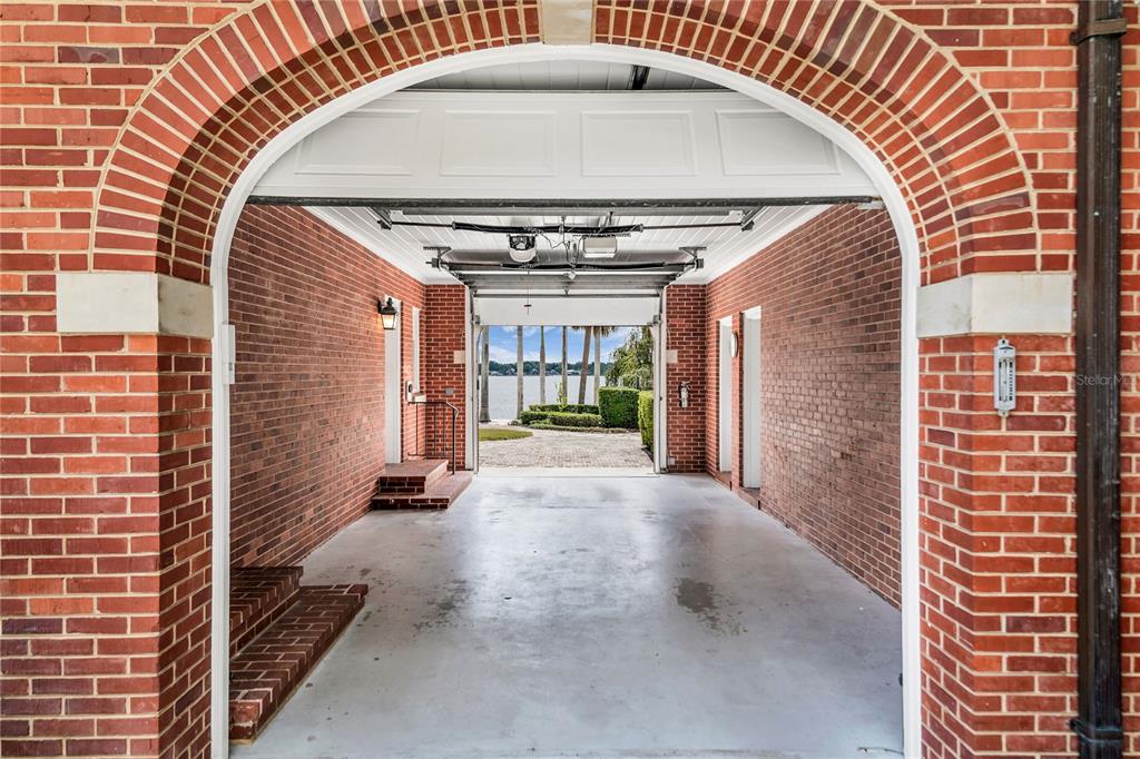 A brick-walled garage with an arched entrance leads to a view of a lake — 1530 WATERWITCH DRIVE, ORLANDO, FL