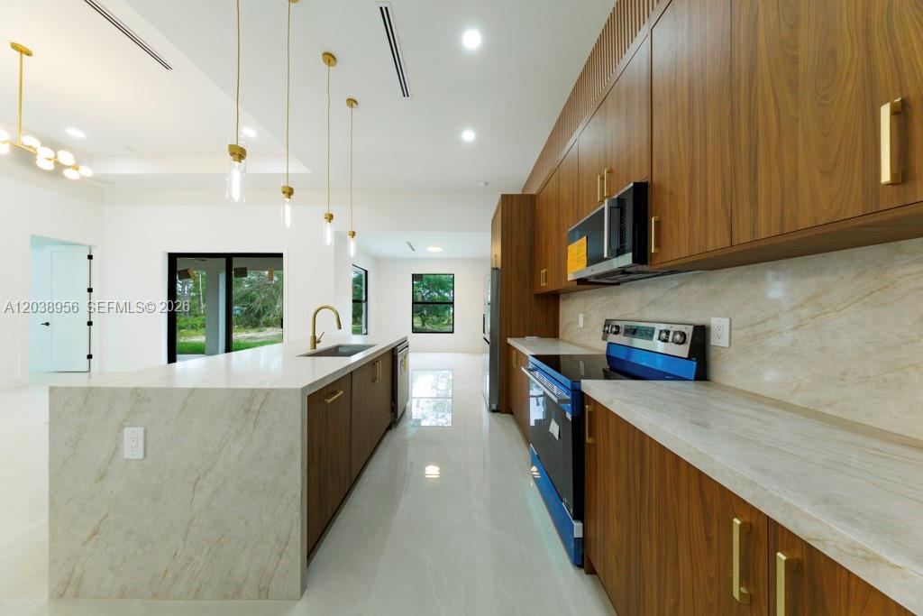 A modern kitchen features wood-toned cabinetry, a marble-patterned island, and white tile flooring — 814 Calyton Ave, Lehigh Acres FL 33972, LEHIGH ACRES, FL