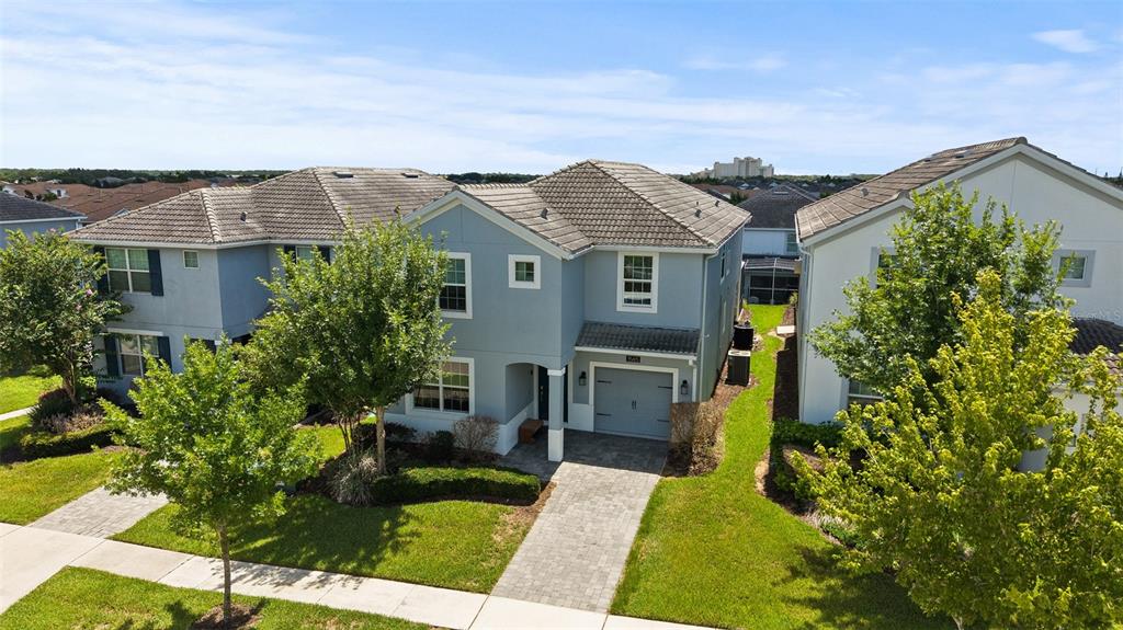 An aerial view shows a two-story blue house with a gray roof and paved driveway — 1565 FLANGE DRIVE, DAVENPORT, FL