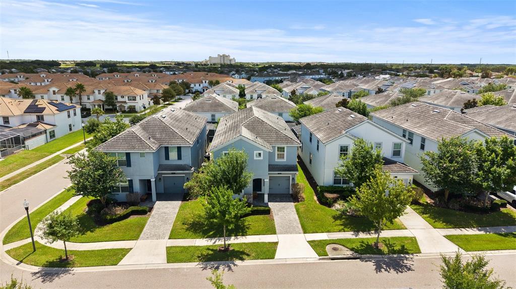 An aerial view shows three suburban houses with gray roofs and paved driveways — 1565 FLANGE DRIVE, DAVENPORT, FL