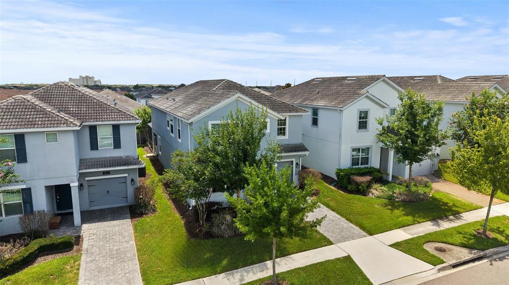 An aerial view shows three two-story suburban houses with gray roofs and paved driveways — 1565 FLANGE DRIVE, DAVENPORT, FL