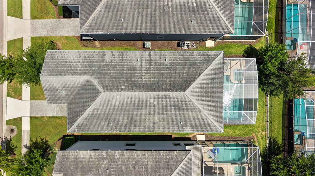 An aerial view shows a residential house with a gray roof and a screened-in pool — 1565 FLANGE DRIVE, DAVENPORT, FL