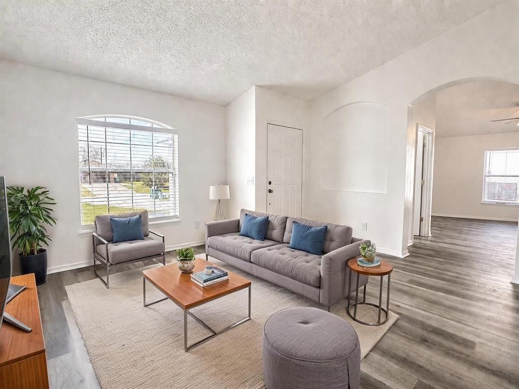 A living room features a gray sofa, armchair, wood coffee table, and light wood flooring — 2871 LOCKWOOD BOULEVARD, DELTONA, FL