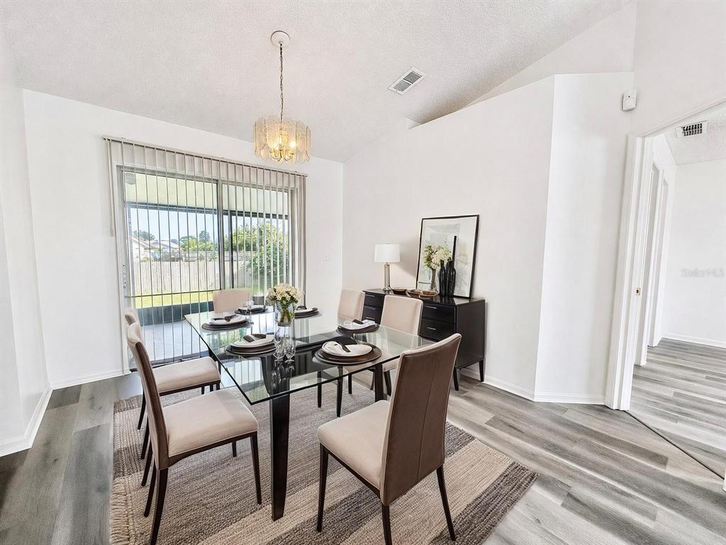 A dining room features a glass table, six chairs, a rug, and a sliding glass door — 2871 LOCKWOOD BOULEVARD, DELTONA, FL