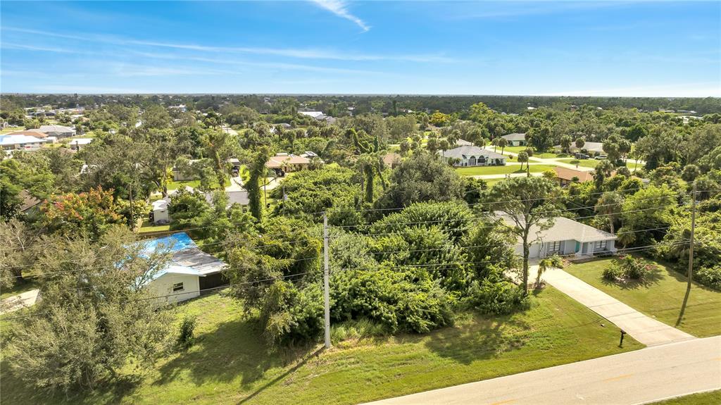 An aerial view shows two houses separated by a dense, tree-filled vacant lot — 18571 EDGEWATER DRIVE, PORT CHARLOTTE, FL