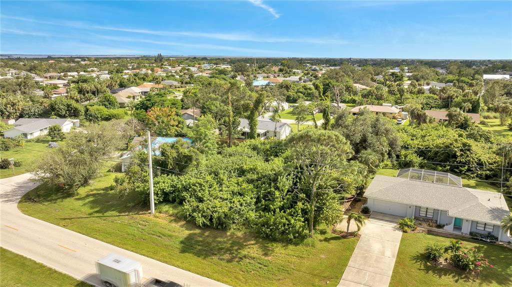 An aerial view shows a suburban neighborhood with a vacant lot between two single-family homes — 18571 EDGEWATER DRIVE, PORT CHARLOTTE, FL