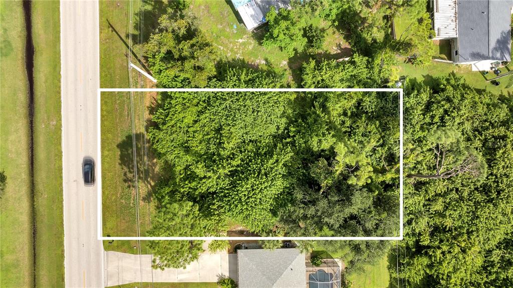 An aerial view shows a rectangular, tree-covered vacant lot bordered by a road and houses — 18571 EDGEWATER DRIVE, PORT CHARLOTTE, FL