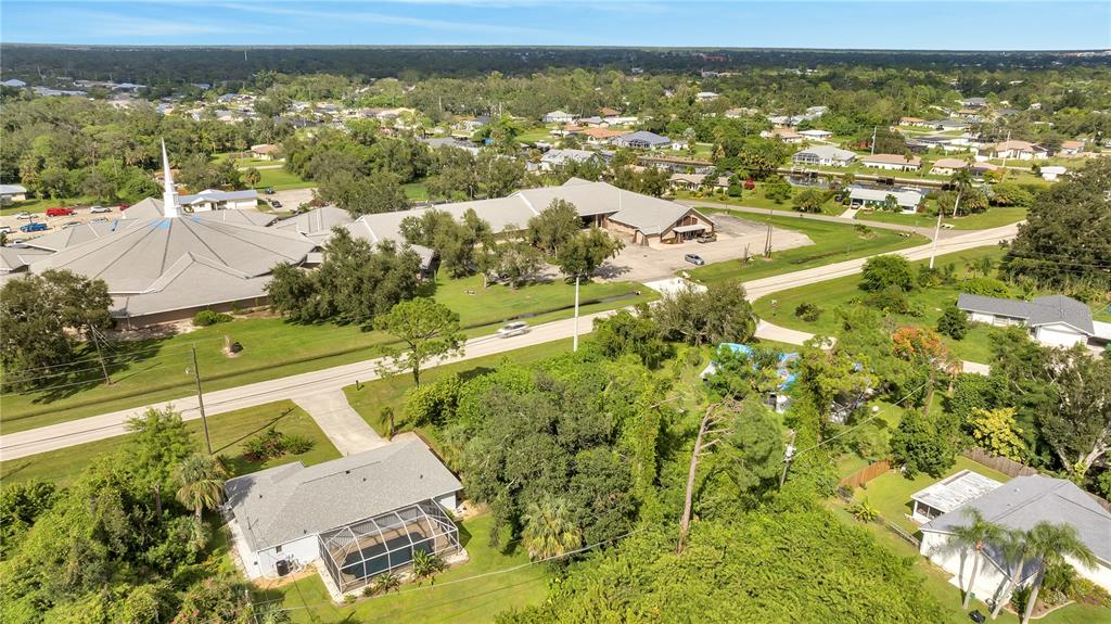 An aerial view shows a residential house with a pool near a large church building — 18571 EDGEWATER DRIVE, PORT CHARLOTTE, FL