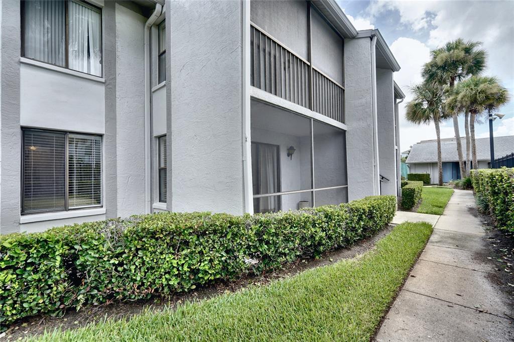 A two-story apartment building features a screened-in patio, a hedge, and a concrete walkway — 1716 PINE RIDGE ROAD UNIT F1, SANFORD, FL