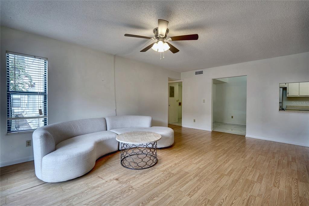 A living room with light wood flooring, a curved sofa, a coffee table, and ceiling fan — 1716 PINE RIDGE ROAD UNIT F1, SANFORD, FL