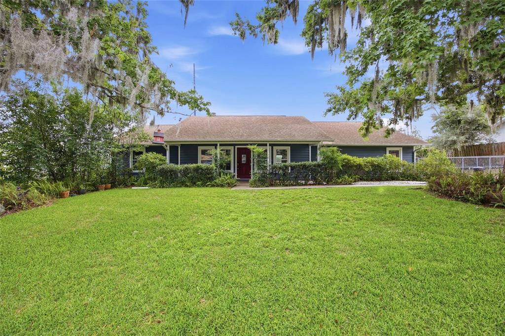 A single-story blue house with a red front door sits behind a large green lawn — 155 SE 32ND PLACE, OCALA, FL
