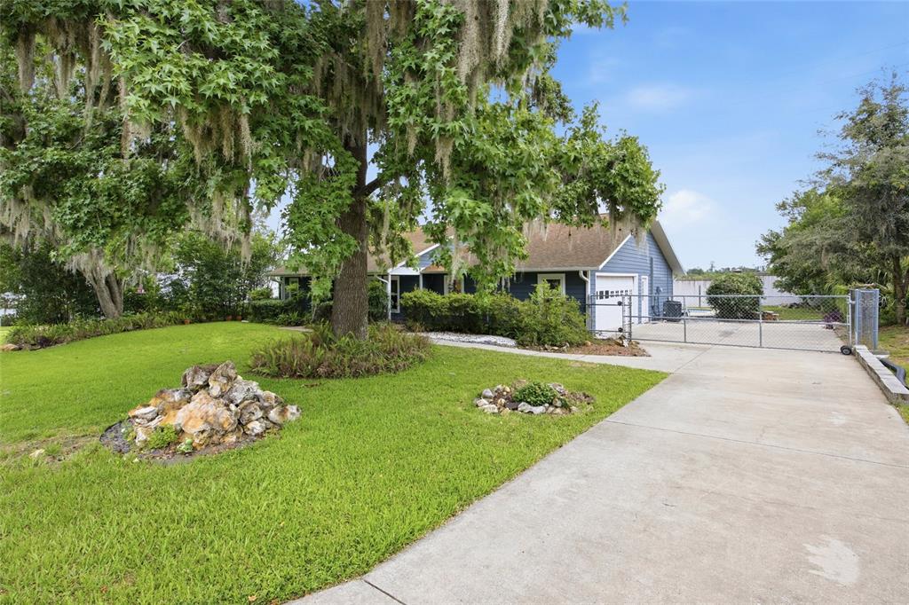 A blue house with a concrete driveway and a large tree in the front yard — 155 SE 32ND PLACE, OCALA, FL