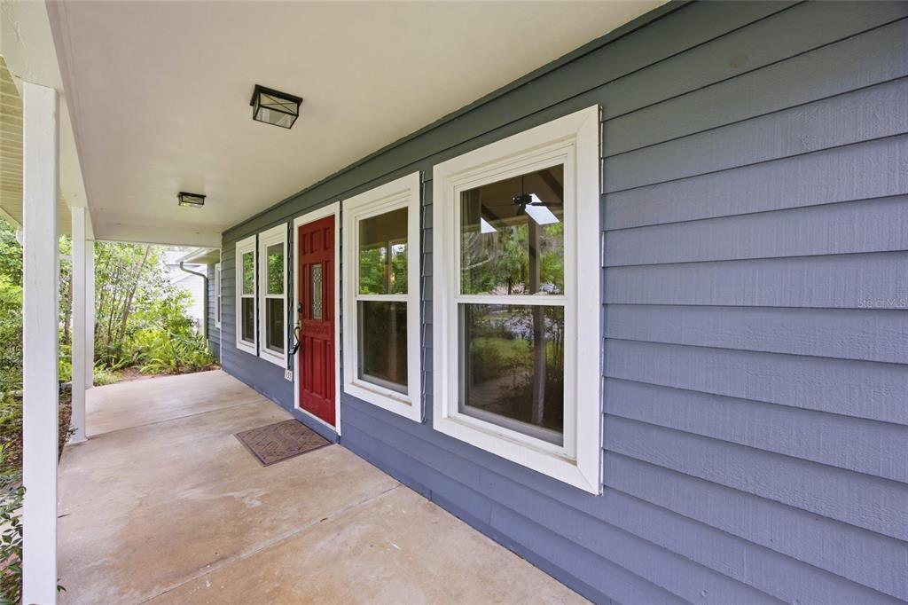 A covered porch features blue horizontal siding, a red front door, and white-trimmed windows — 155 SE 32ND PLACE, OCALA, FL
