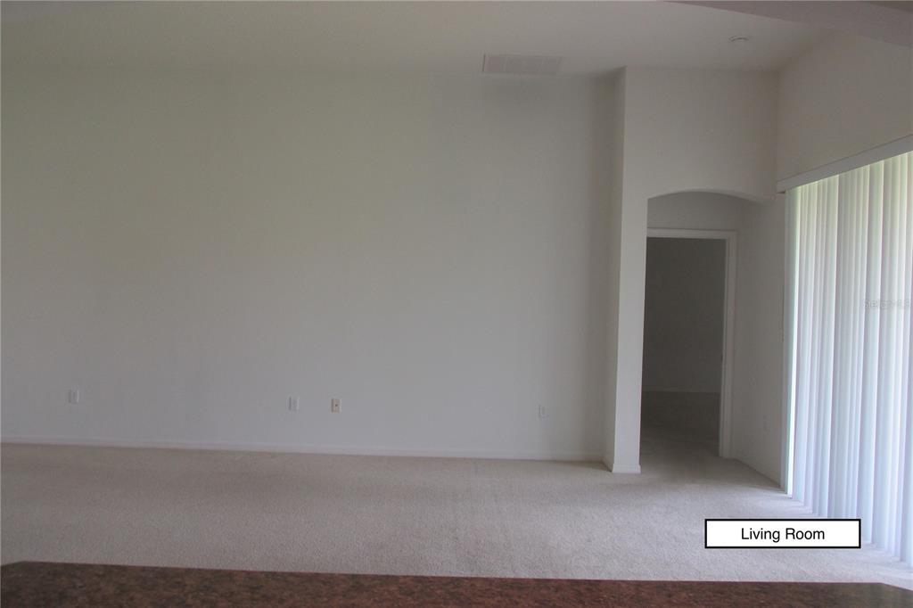 A living room with beige carpet, white walls, and a doorway leading to another room — 3838 GOLDEN KNOT DRIVE, KISSIMMEE, FL