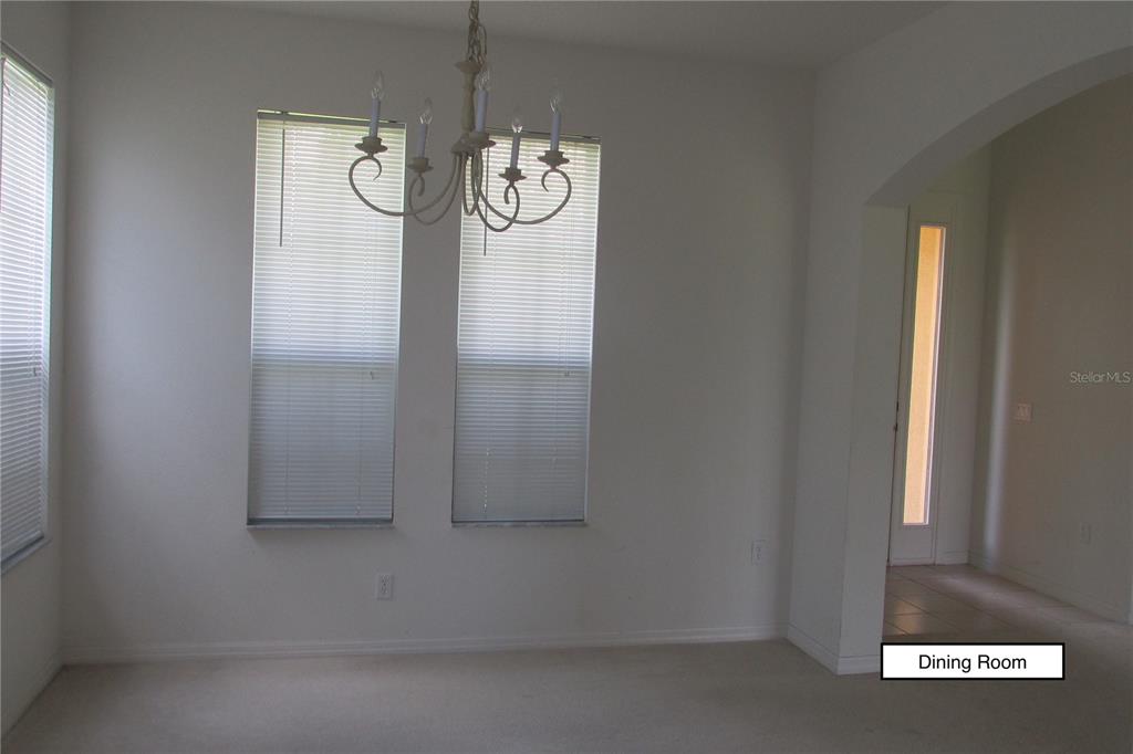 A dining room with white walls, carpeted flooring, a chandelier, and two windows with blinds — 3838 GOLDEN KNOT DRIVE, KISSIMMEE, FL