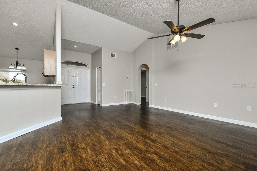 A living room with vaulted ceilings, dark wood-look flooring, and a ceiling fan — 6025 LIVE OAK DRIVE, WINTER HAVEN, FL