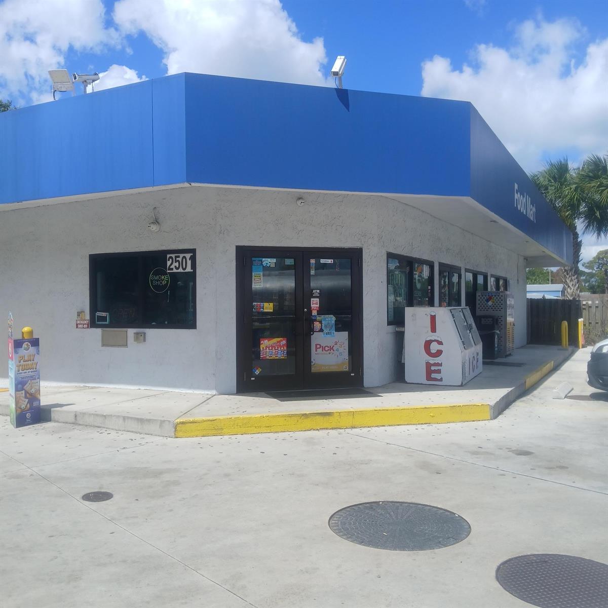 A corner view of a white commercial building with a blue awning and glass doors — 2501 Orange Avenue, Fort Pierce FL 34947, FORT PIERCE, FL