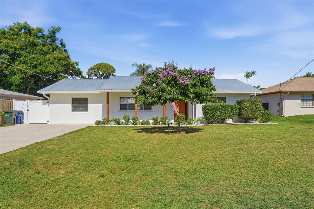 A single-story white house with a metal roof and a flowering tree in the yard — 2600 CAMBRIDGE DRIVE, SARASOTA, FL