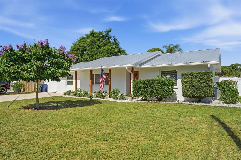 A white single-story house with a metal roof and a front yard with a tree — 2600 CAMBRIDGE DRIVE, SARASOTA, FL