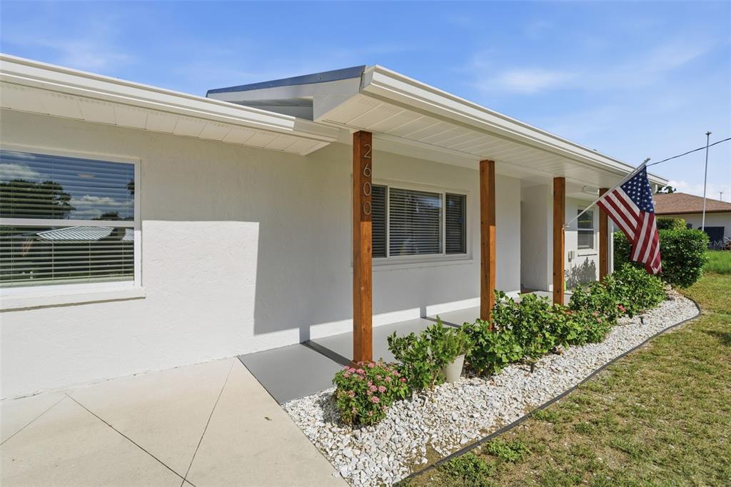 A white house exterior features a covered porch with wooden posts and a front yard — 2600 CAMBRIDGE DRIVE, SARASOTA, FL