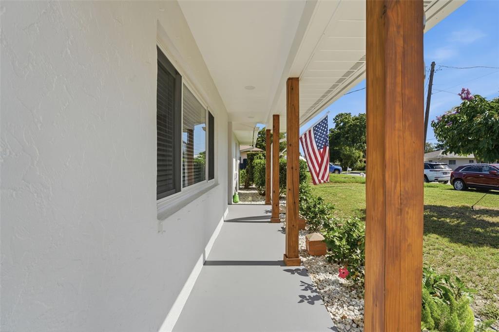 A covered porch with wooden support posts and a gray floor overlooks a grassy yard — 2600 CAMBRIDGE DRIVE, SARASOTA, FL