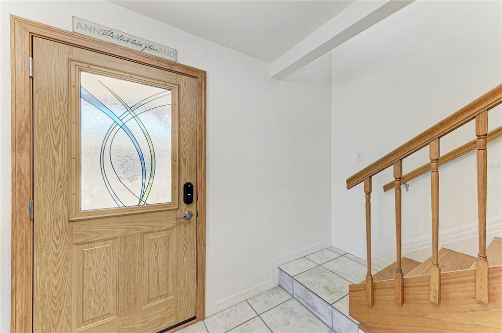 An entryway features a wood-framed glass door, tiled floor, and a wooden staircase — 872 NORTH SHORE DRIVE, ANNA MARIA, FL