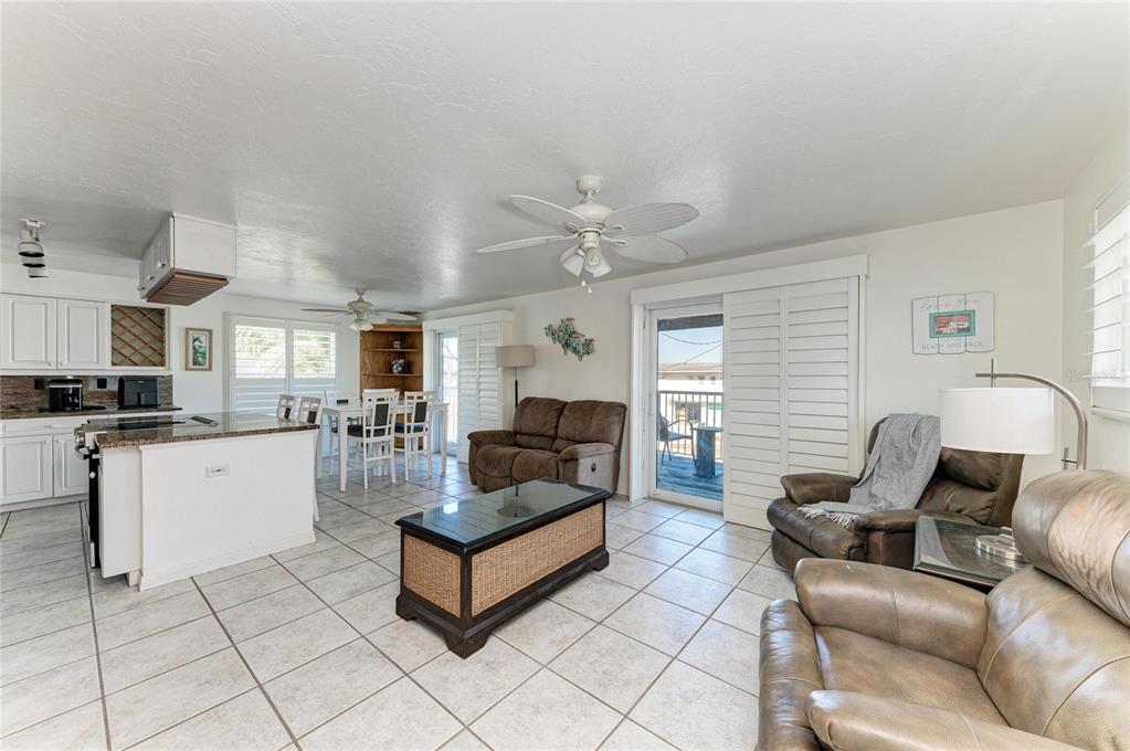 An open-concept living and dining area features tile floors, white cabinetry, and leather furniture — 872 NORTH SHORE DRIVE, ANNA MARIA, FL