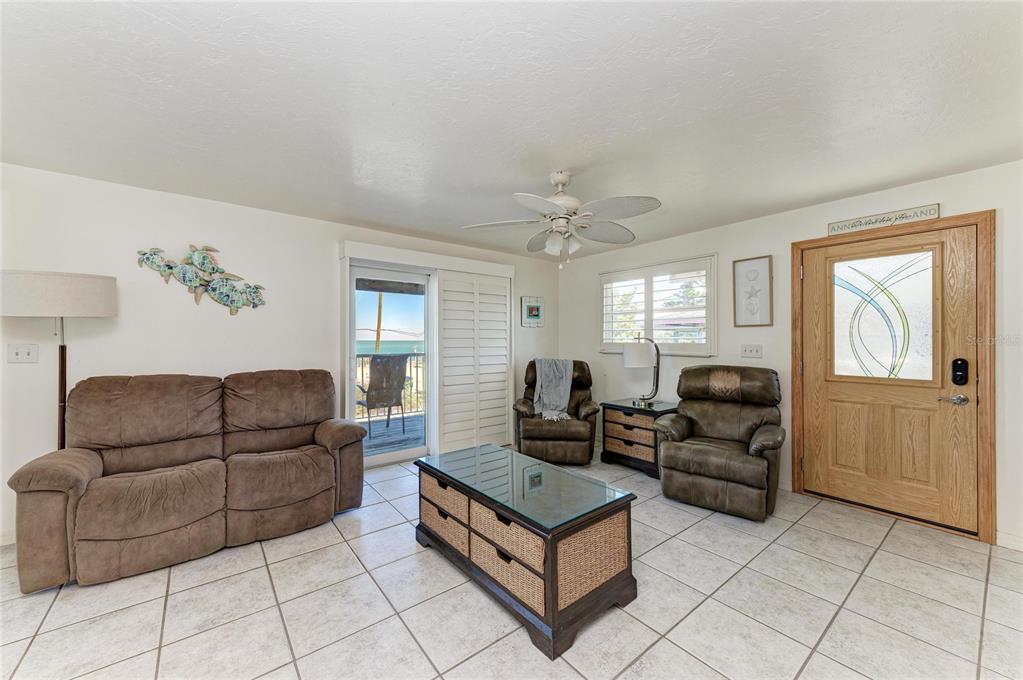 A living room features tile flooring, a brown sofa, two recliners, and a glass-topped coffee table — 872 NORTH SHORE DRIVE, ANNA MARIA, FL
