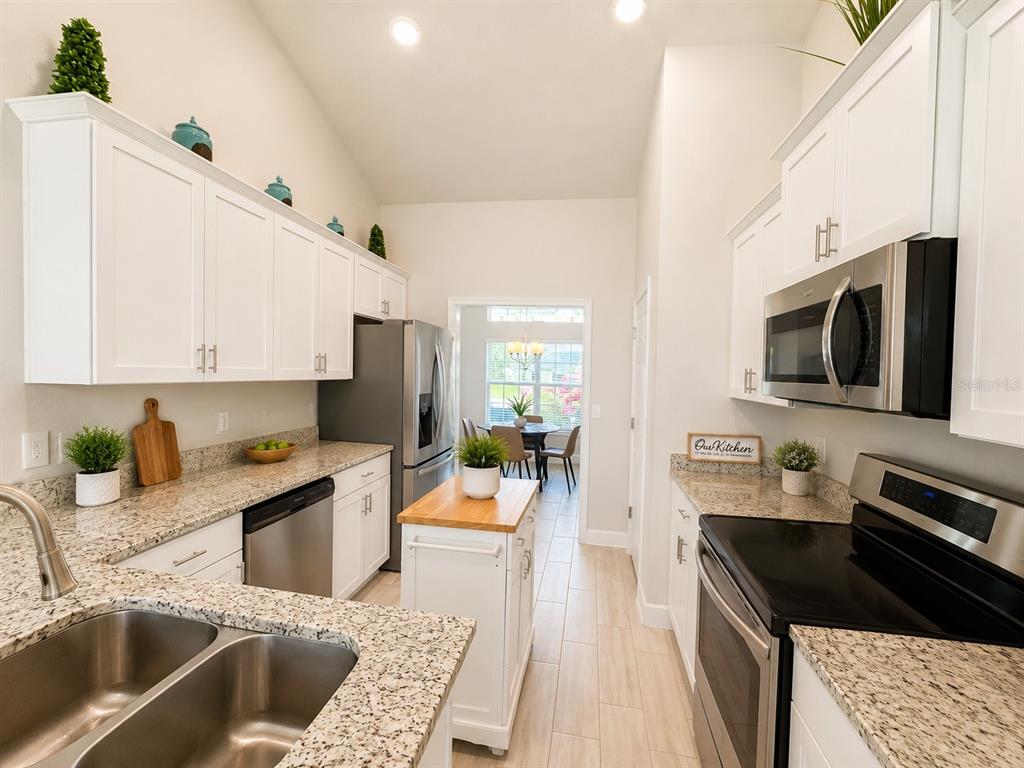 A kitchen features white cabinets, granite countertops, stainless steel appliances, and a central island — 4869 SW 115TH STREET, OCALA, FL
