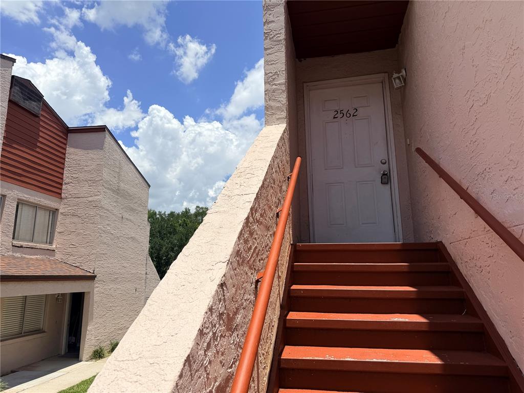 An exterior view shows a set of stairs leading to a white front door — 2562 LAKEWAY BRANCH DRIVE UNIT 3002, ORLANDO, FL