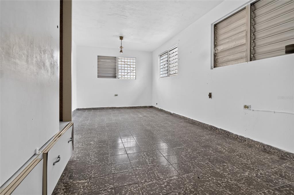 An empty room features white walls, tiled floors, and two windows with louvered shutters — 3 URBANIZACIÓN REPARTO MARQUEZ UNIT BLQ B7, ARECIBO, PR