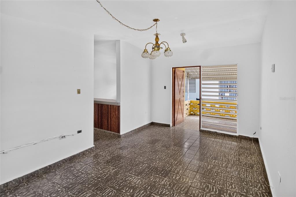 An empty room with dark tiled floors, a chandelier, and an open doorway to a balcony — 3 URBANIZACIÓN REPARTO MARQUEZ UNIT BLQ B7, ARECIBO, PR