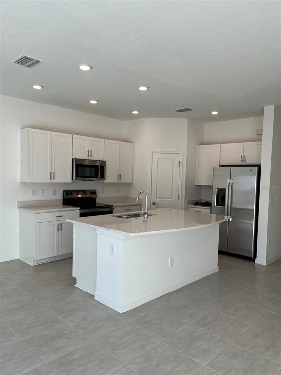 A kitchen features white cabinets, stainless steel appliances, and a central island with a sink — 5845 BISCOTTI ST, NOKOMIS, FL