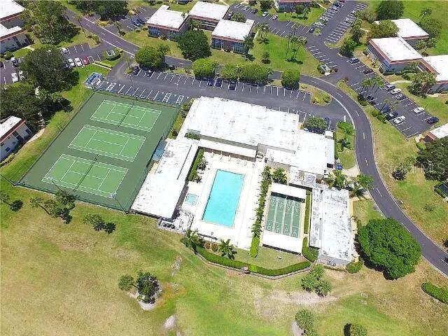 Aerial view of a community recreation area featuring tennis courts, a swimming pool, and buildings — 94 SPRING LAKE DRIVE UNIT 203, VERO BEACH, FL
