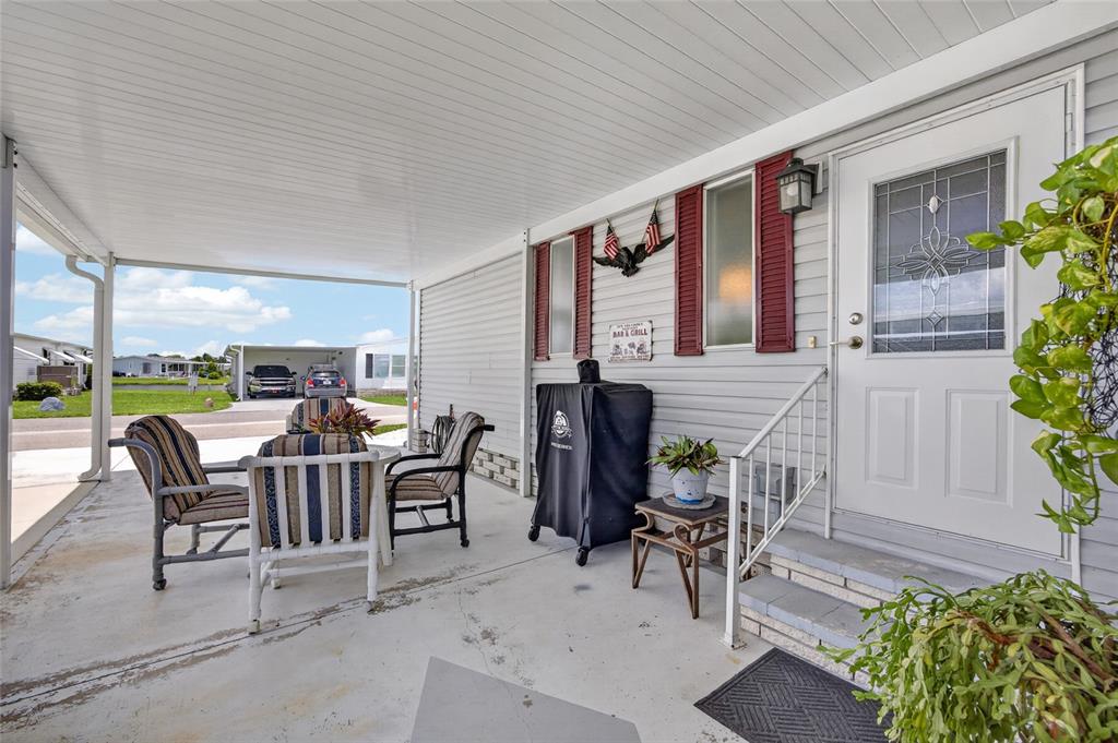A covered patio features outdoor furniture, a grill, and a white front door with shutters — 644 SCHOONER STREET, NORTH PORT, FL